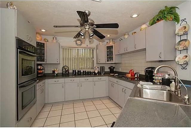 kitchen with light tile patterned flooring, sink, decorative backsplash, ceiling fan, and stainless steel double oven