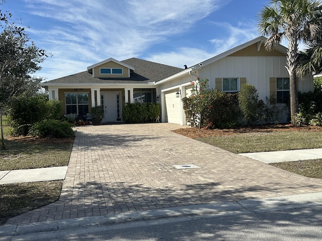 view of front of home with decorative driveway, a garage, and roof with shingles