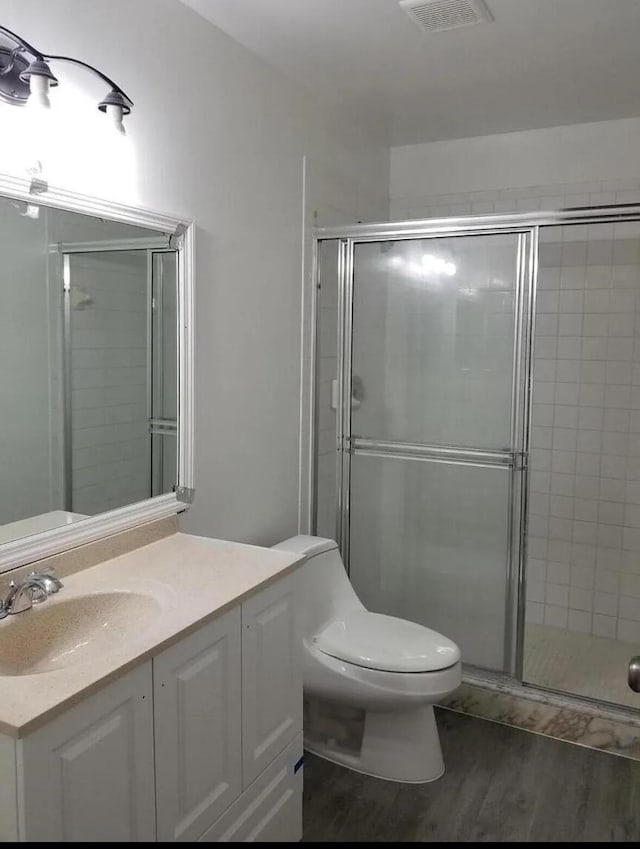 bathroom featuring vanity, hardwood / wood-style floors, walk in shower, and toilet