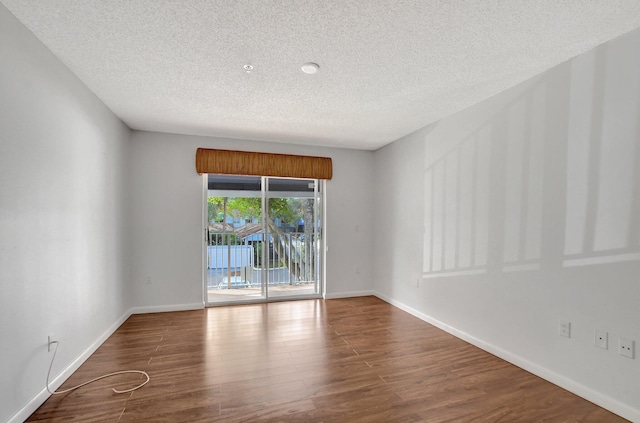 empty room with dark wood-type flooring and a textured ceiling