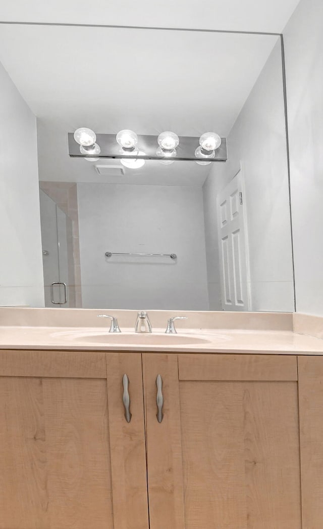 bathroom with a shower with door and vanity