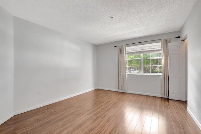 spare room featuring hardwood / wood-style floors and a textured ceiling