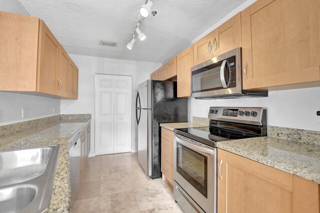 kitchen with stainless steel appliances, sink, a textured ceiling, and kitchen peninsula