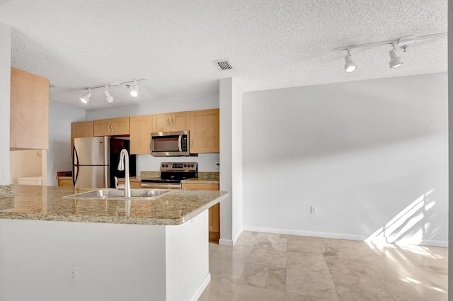 kitchen with stainless steel appliances, kitchen peninsula, a textured ceiling, and light brown cabinets