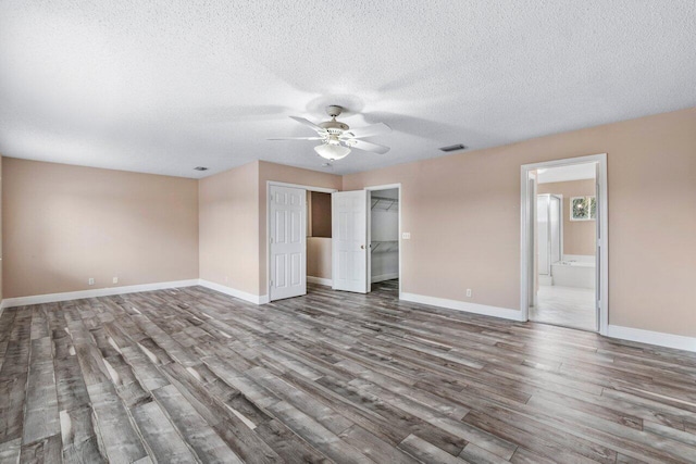 unfurnished bedroom with hardwood / wood-style floors, connected bathroom, ceiling fan, a textured ceiling, and a closet