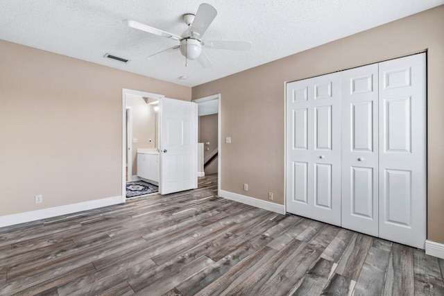 unfurnished bedroom with hardwood / wood-style flooring, ceiling fan, a closet, and a textured ceiling