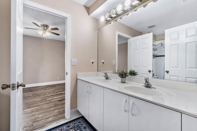 bathroom with vanity, ceiling fan, a textured ceiling, and walk in shower