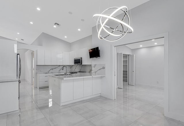 kitchen featuring white cabinetry, hanging light fixtures, high vaulted ceiling, decorative backsplash, and kitchen peninsula