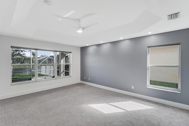 carpeted spare room featuring a raised ceiling and ceiling fan