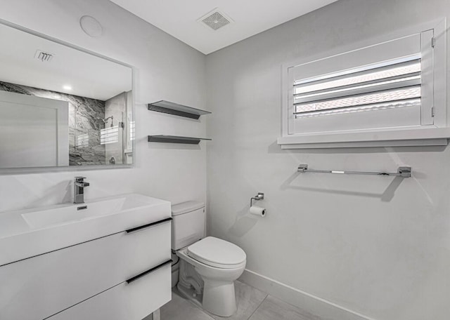 bathroom with tiled shower, vanity, and toilet