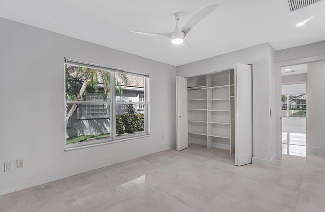 unfurnished bedroom featuring multiple windows, ceiling fan, and a closet