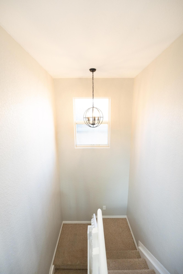 stairway featuring a chandelier, carpet flooring, and baseboards