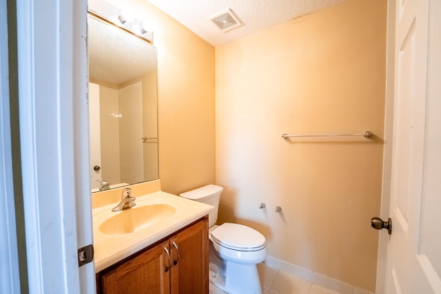 bathroom with vanity, toilet, tile patterned flooring, and a textured ceiling