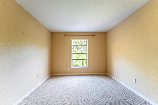 unfurnished room with baseboards, a textured wall, and carpet flooring