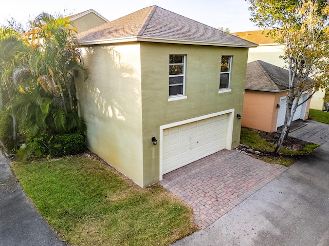 view of property exterior with a garage, roof with shingles, stucco siding, and decorative driveway