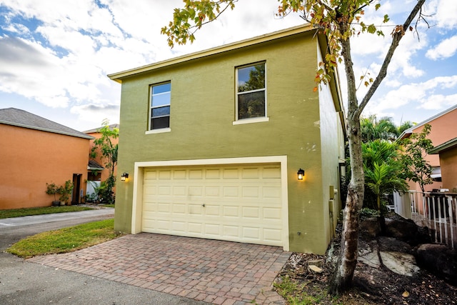 exterior space with stucco siding, an attached garage, and decorative driveway
