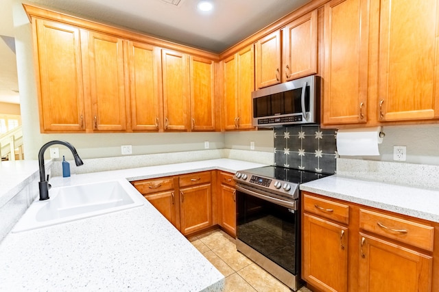 kitchen with stainless steel appliances, light tile patterned flooring, sink, and light stone counters