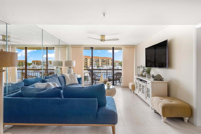 living room featuring expansive windows, ceiling fan, and a water view