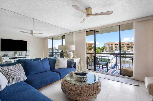 living room with expansive windows, a water view, ceiling fan, and a textured ceiling