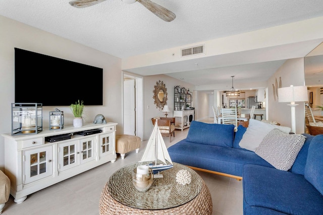 living room with ceiling fan with notable chandelier and a textured ceiling