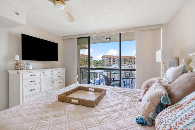 bedroom with access to exterior, a textured ceiling, expansive windows, and ceiling fan