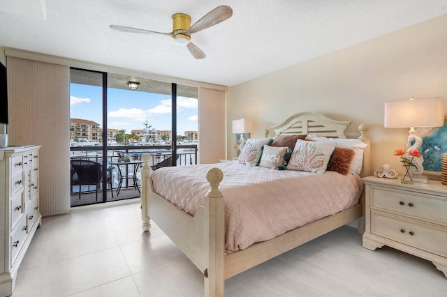 bedroom with access to exterior, a textured ceiling, expansive windows, and ceiling fan