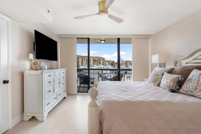 bedroom featuring ceiling fan, a wall of windows, access to exterior, and a textured ceiling