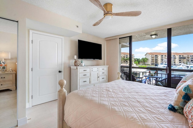 bedroom with ceiling fan, floor to ceiling windows, a textured ceiling, and access to outside