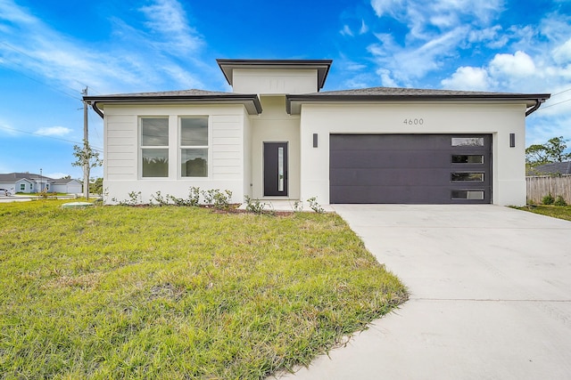 prairie-style house featuring a garage and a front lawn