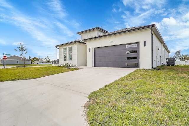 view of front of house featuring a garage, a front yard, and central air condition unit