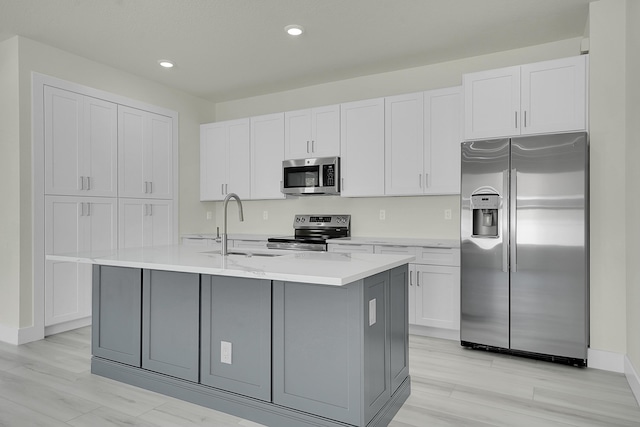 kitchen featuring appliances with stainless steel finishes, sink, a center island with sink, and white cabinets