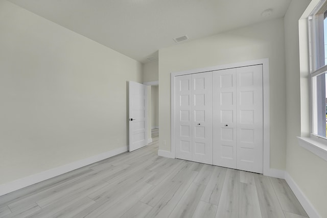 unfurnished bedroom with light hardwood / wood-style floors and a closet