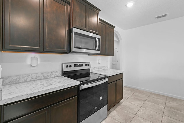 kitchen with dark brown cabinetry, visible vents, arched walkways, appliances with stainless steel finishes, and light countertops