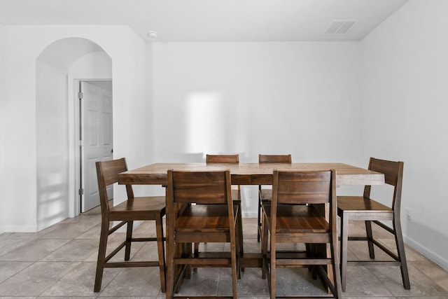 dining space featuring baseboards, visible vents, and arched walkways