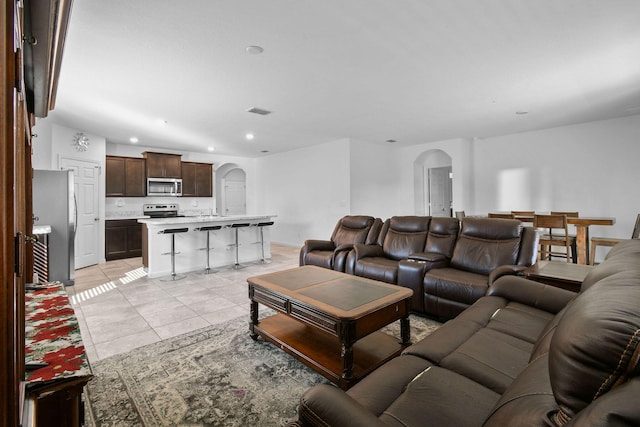 living room featuring arched walkways, visible vents, recessed lighting, and light tile patterned floors