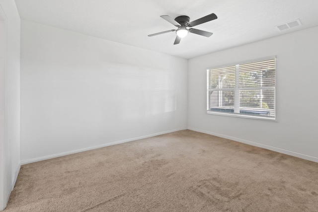 carpeted empty room featuring ceiling fan, visible vents, and baseboards