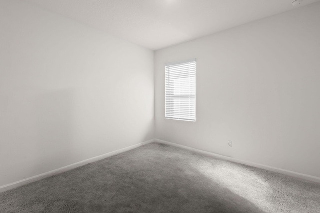 spare room featuring carpet flooring and baseboards