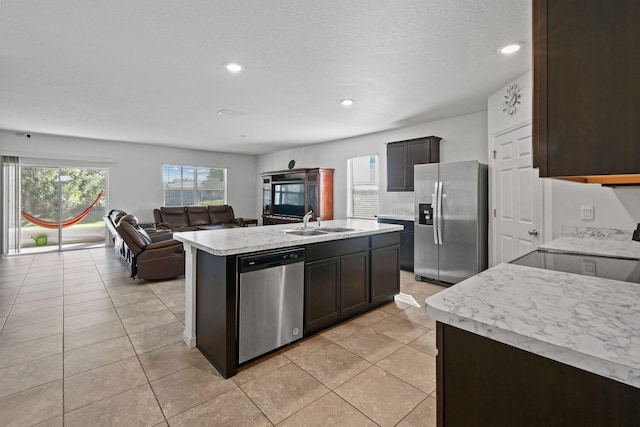 kitchen with open floor plan, stainless steel appliances, a sink, and light countertops