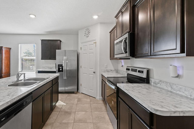 kitchen with dark brown cabinets, appliances with stainless steel finishes, a sink, and light countertops