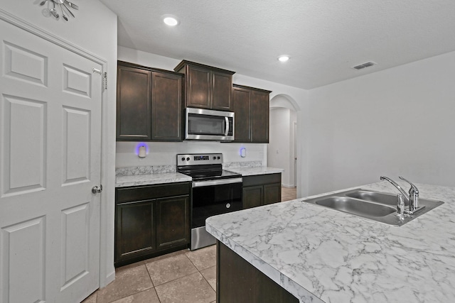 kitchen featuring arched walkways, stainless steel appliances, light countertops, visible vents, and a sink