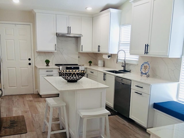 kitchen featuring sink, dishwasher, a center island, light stone counters, and white cabinets