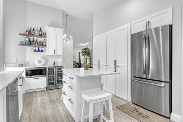 kitchen featuring a sink, dishwashing machine, under cabinet range hood, and white cabinetry