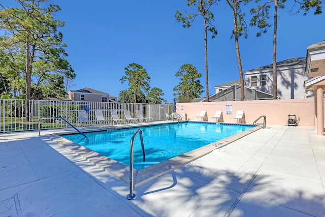 pool with a patio area and fence