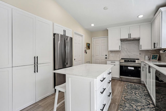 kitchen featuring white cabinetry, light stone countertops, stainless steel appliances, and a center island