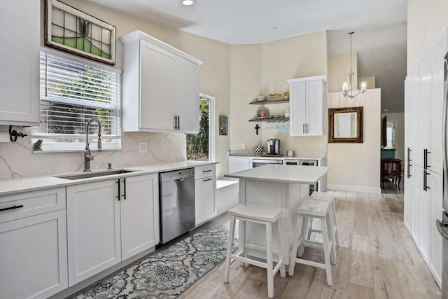 kitchen featuring white cabinetry, stainless steel dishwasher, sink, and hanging light fixtures