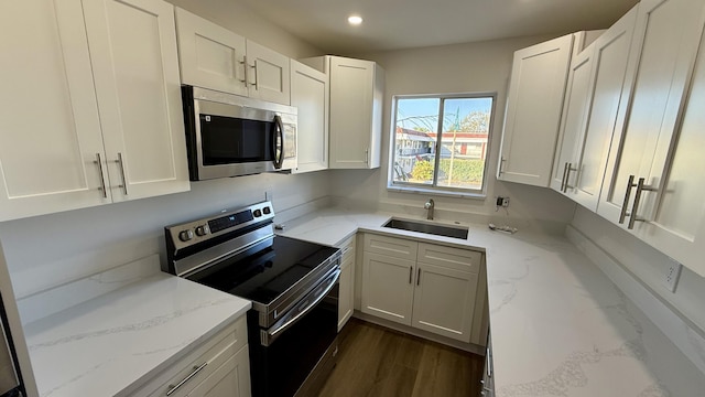 kitchen featuring sink, white cabinets, dark hardwood / wood-style flooring, stainless steel appliances, and light stone countertops