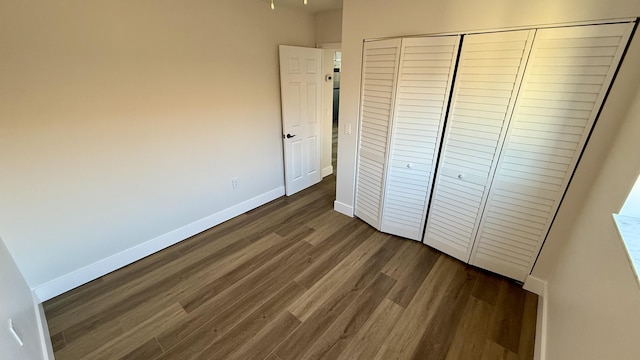 unfurnished bedroom with dark wood-type flooring and a closet