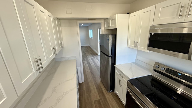 kitchen with dark wood-type flooring, appliances with stainless steel finishes, light stone countertops, and white cabinets