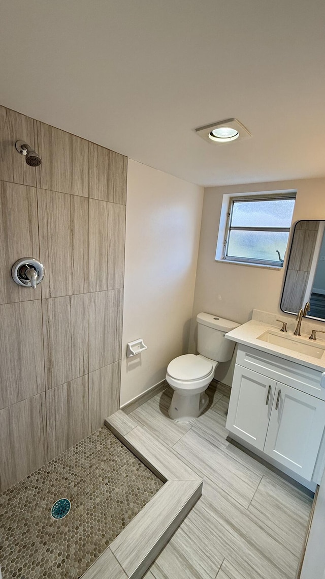 bathroom with vanity, toilet, and a tile shower