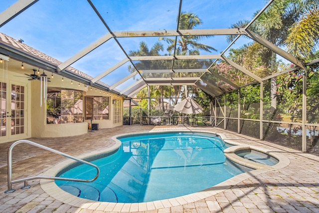 view of pool featuring ceiling fan, a patio, glass enclosure, and an in ground hot tub